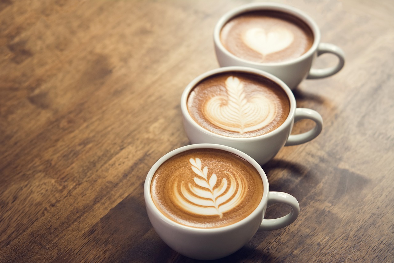 three white coffee cups with latte art on a wooden table